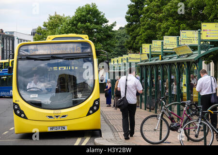 Yellow Buses at bus stops with passengers waiting in the city centre. Bournemouth, Dorset, England, UK, Britain Stock Photo