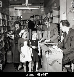 1950s, historical, local people inside a mobile library, London, England, with two young girls borrowing a book at the counter. Stock Photo