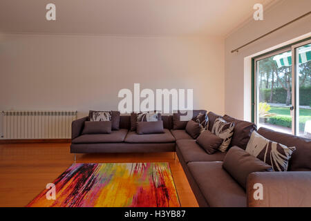 Modern living room with big brown sofa and luminous large window Stock Photo