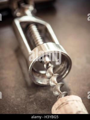Corkscrew and cork on stone table in close up. Stock Photo
