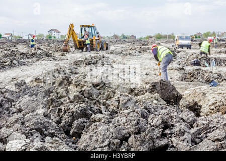 Zrenjanin, Vojvodina, Serbia - June 14, 2015: Backhoe tractor is working on a construction site. Group of workers with shovels a Stock Photo