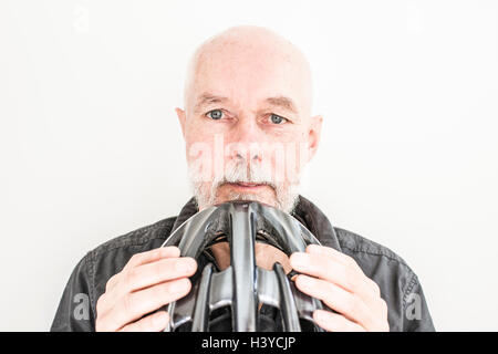 Close up of old man holding a bicycle helmet. Portrait of elderly person living an active life with healthy lifestyle. Stock Photo