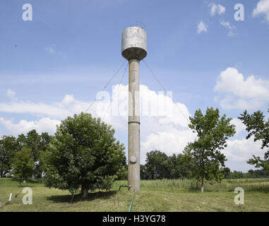 Silver Water Tower among green grass and trees. Stock Photo