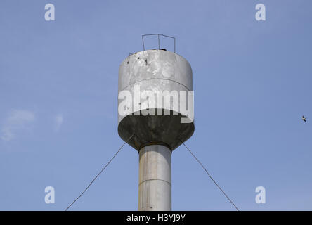 Silver Water Tower among green grass and trees. Stock Photo