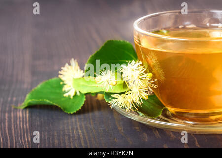 Linden tea on a wooden table in a glass cup close up. Flower tea, herbal medicine. Stock Photo