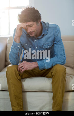 Depressed man sitting on sofa Stock Photo