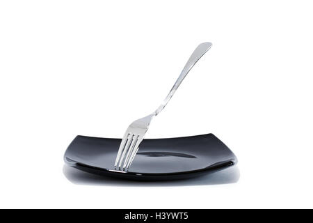 Steel shiny fork on nice empty black plate against white background Stock Photo