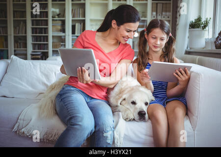 Mother and daughter sitting with pet dog and using digital Stock Photo