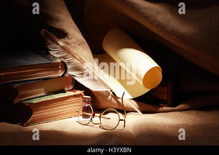 Stack of old books near quill and scroll on canvas background Stock Photo