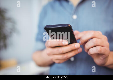 Midsection of businessman texting on cellphone at creative office Stock Photo
