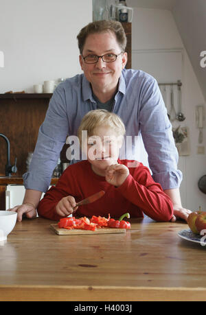Portrait of father and boy at table in kitchen Stock Photo