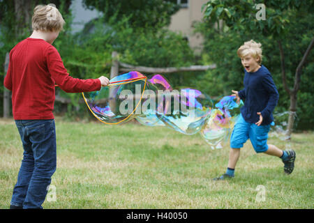 Happy brothers playing with soap bubble in back yard Stock Photo