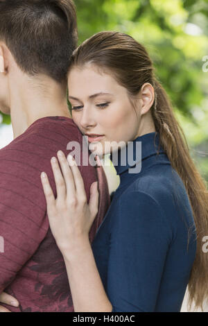 Thoughtful woman leaning on boyfriend's back at park Stock Photo