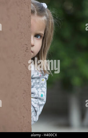 Portrait of girl standing behind wall Stock Photo