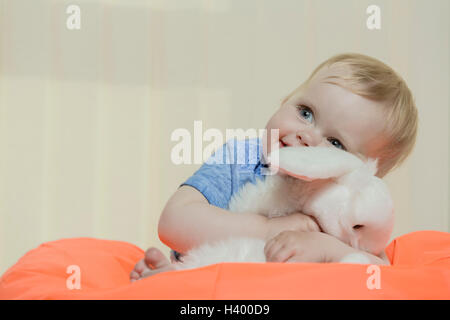 Close-up of cute smiling girl holding stuffed toy while sitting on bean bag at home Stock Photo