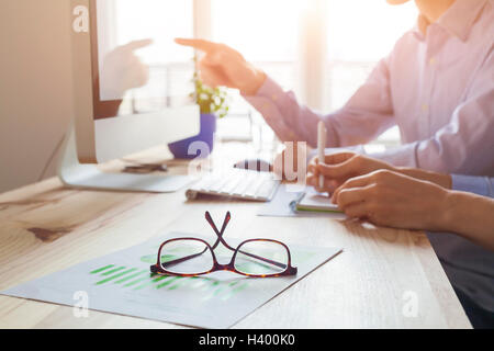 Sunset atmosphere in co-working office, business meeting with two people, close-up on glasses Stock Photo
