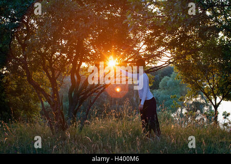 Woman practicing relaxation exercise on field during sunny day Stock Photo
