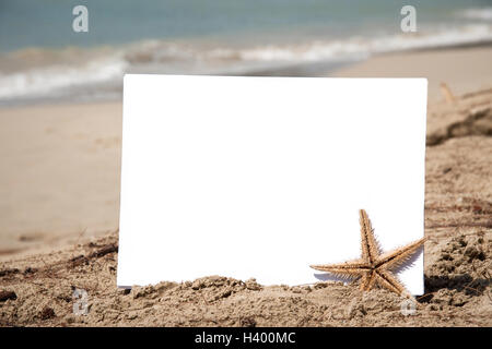 Blank piece of paper with a starfish on the sand with sea background Stock Photo