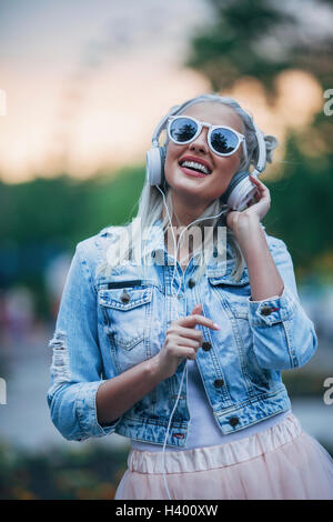 Happy fashionable woman wearing sunglasses while listening to music through headphones Stock Photo