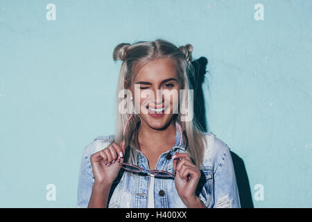 Portrait of beautiful young woman winking while holding sunglasses Stock Photo