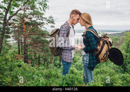 Loving couple holding hands while standing amidst plants at forest Stock Photo