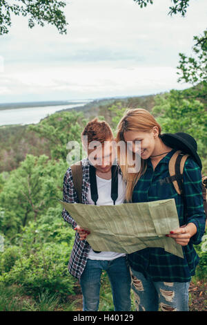 Smiling couple reading map while hiking in forest Stock Photo