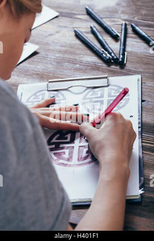 Tattoo artist drawing designs at table in art studio Stock Photo