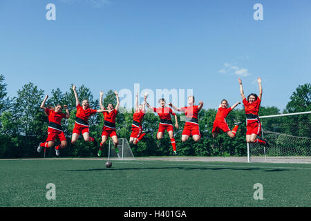Happy soccer team cheering on field against sky Stock Photo