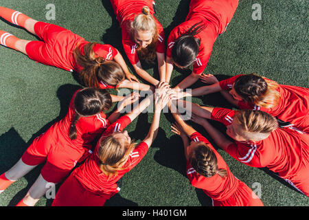High angle view of sports team stacking hands on field Stock Photo