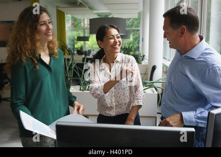 Happy business colleagues discussing over document at office desk Stock Photo