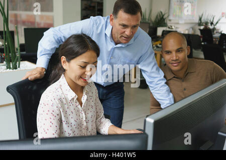 Smiling business people looking at computers during meeting at creative office Stock Photo