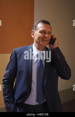 Confident businessman using mobile phone while standing at office Stock Photo