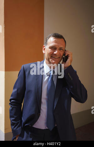Happy businessman using mobile phone while standing at office Stock Photo
