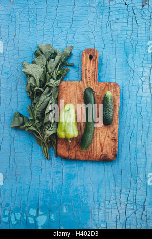 Directly above shot of fresh green vegetables with cutting board on wooden table Stock Photo