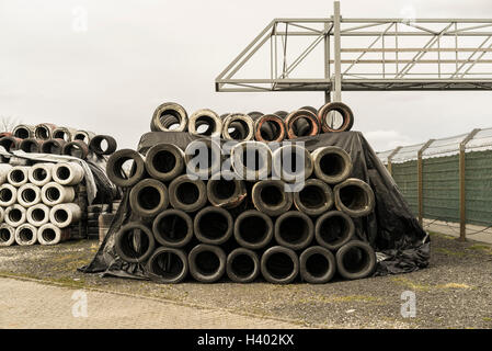 Stack of old tires on field against clear sky Stock Photo