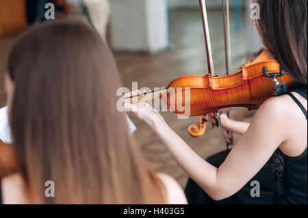 The hand of the girl playing the violin in dark colors Stock Photo