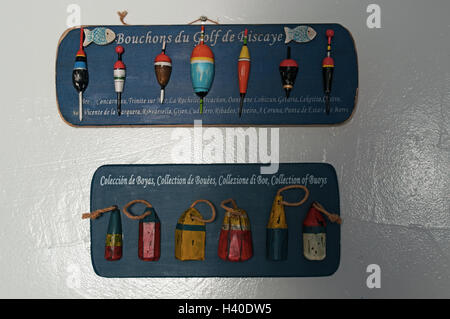 Interior decoration: wooden panels with a collection of buoys, corks and floats for fishing on a white wall Stock Photo