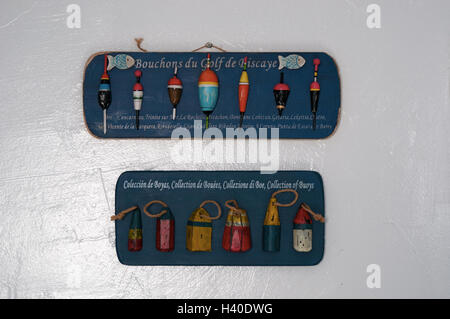 Interior decoration: wooden panels with a collection of buoys, corks and floats for fishing on a white wall Stock Photo