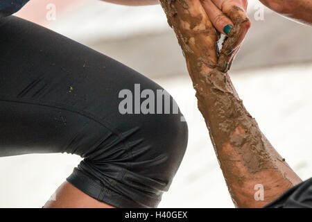 Two male Tough Mudder competitors offering help at an obstacle climbing the angle wall Pyramid Scheme Stock Photo