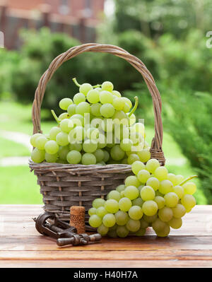 White grape basket on wooden table in sunny garden Stock Photo