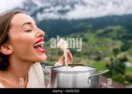 Woman with fondue in the mountains Stock Photo