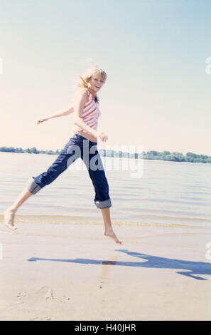 Woman, leisurewear, run, sandy beach, caper, 20-30 years, 20 years, young, jeans, top, motion, melted, activity, fitness, fun, amusement, cheerfulness, vitality, jump, crack, joy life, happy, leisure time, vacation, beach vacation, summer Stock Photo