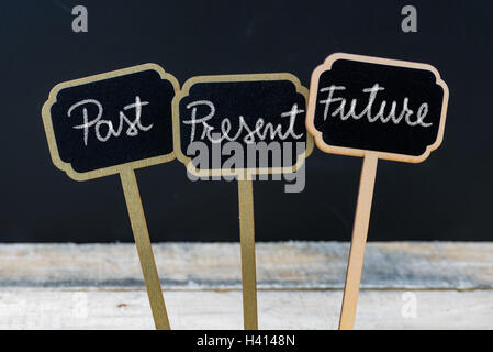 Business message Past, Present, Future written with chalk on wooden mini blackboard labels, defocused chalkboard and wood table Stock Photo