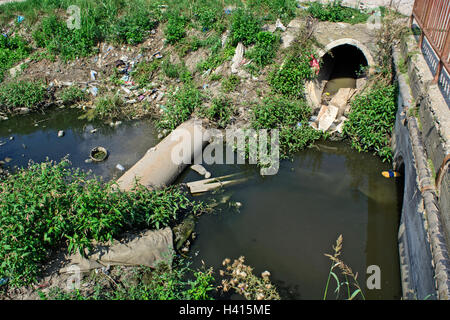 Very polluted river that runs through the village. Stock Photo
