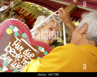 Fair, Senior couple, happy, declaration love, gingerbread heart, fun, amusement, eye contact, senior citizens, couple, 60-70 years, leisure time, carefree, lighthearted, actively, fit, healthy, actively, public festival, feast, spring feast, amusement par Stock Photo