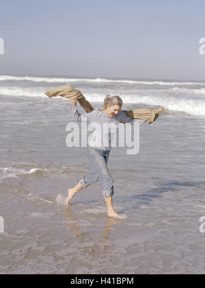 Sandy beach, sea, senior, happy, water shallowly, run, enjoy side view, woman, Best Age, 60-70 years, long-haired, grey-haired, leisurewear, jeans, cloth, Stola, leisure time, lifestyle, rest, recreation, vacation, fun, cheerfulness, cheerfulness, exubera Stock Photo