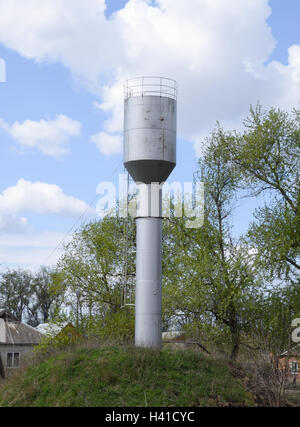 Silver Water Tower among green grass and trees. Stock Photo