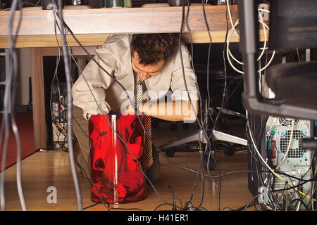 Office, desk, computer, cable, man, floor, kneel, browse garbage can, search office worker, manager, 20-30 years, workplace, clerk, connections, disorderly, computer cable, computer, PC, bucket, waste basket, garbage, waste, search, search, find, note, sl Stock Photo