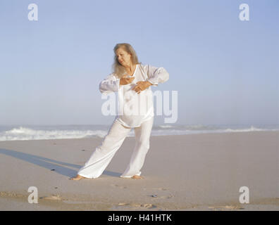 Sandy beach, woman, Tai-Chi, Best Age, 50-60 years, beach, sea, leisure time, hobby, practise, meditative, motion, motion sequences, exercises, slowly, fluently, shadow speakers, 'Free Flow Movement', balance, activity, body consciousness, meditation, Tai Stock Photo