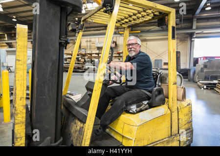 Caucasian worker driving forklift in factory Stock Photo